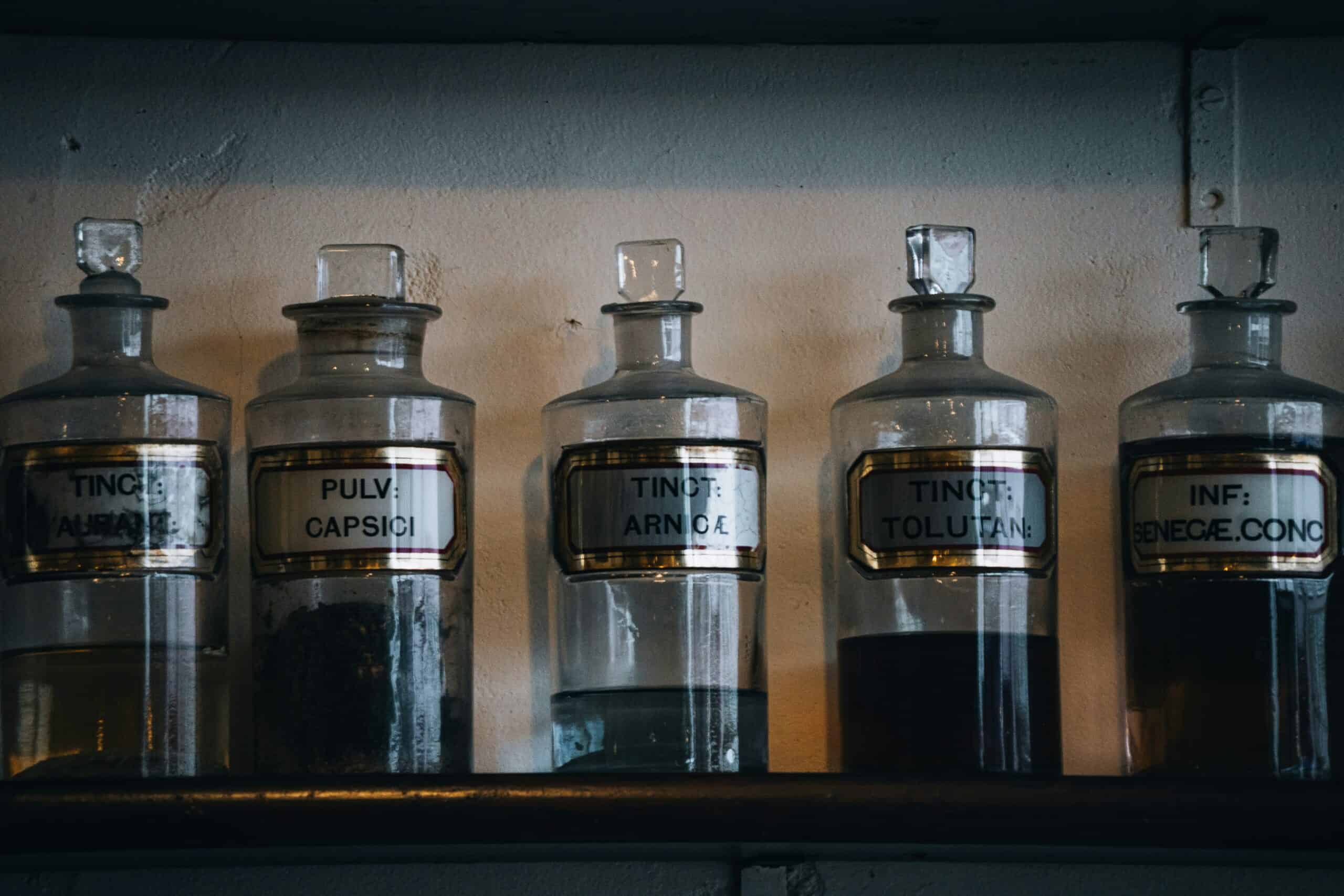 Medication bottles with Latin labels on a shelf in a medical setting.