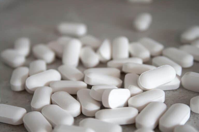 White chewable tablets on a gray surface, medication or supplement pills.