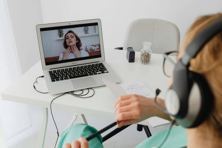 Telehealth consultation with a female patient using headphones and laptop.